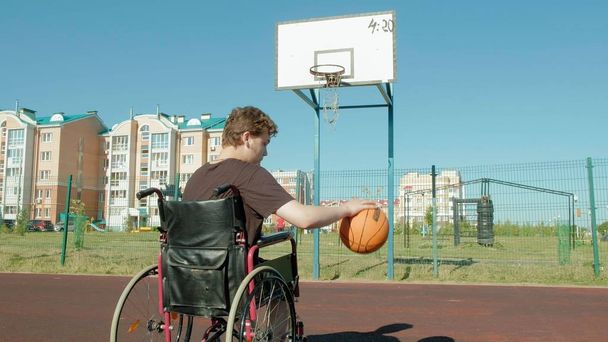 Homem com deficiência joga basquete de sua cadeira de rodas, ao ar livre 4k
 - Foto, Imagem