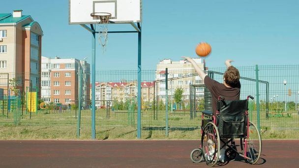 無効に男オープンエアの彼の車椅子からバスケット ボールを果たしています。 - 写真・画像