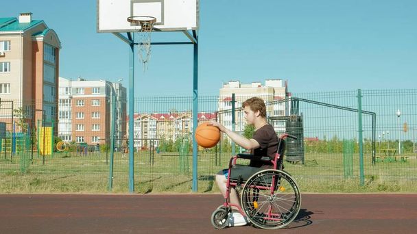 El hombre discapacitado juega baloncesto desde su silla de ruedas, al aire libre
 - Foto, imagen