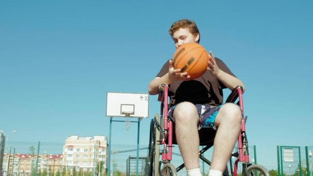 Инвалид играет в баскетбол со своего инвалидного кресла на открытом воздухе
 - Фото, изображение