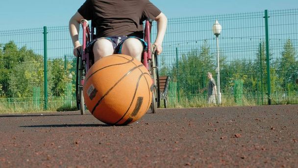 El hombre discapacitado juega baloncesto desde su silla de ruedas, al aire libre
 - Foto, Imagen