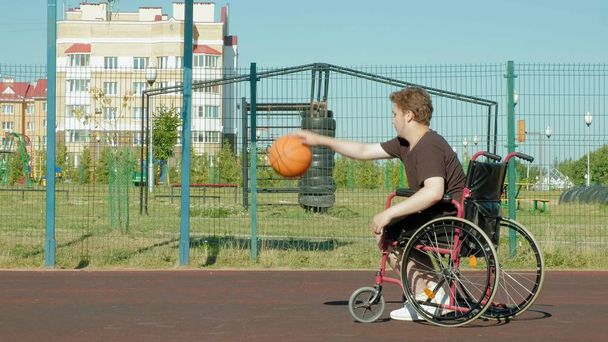 El hombre discapacitado juega baloncesto desde su silla de ruedas, al aire libre
 - Foto, imagen