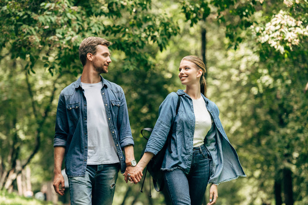 beautiful young couple in denim shirts walking by park - Photo, Image