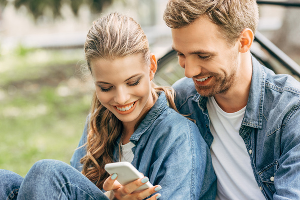 beautiful young couple using smartphone together at park - Foto, Imagen