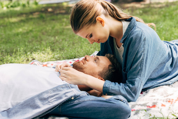 beautiful young couple lying on grass and flirting at park - Foto, imagen