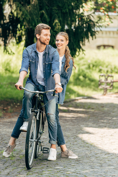 hermosa pareja joven montar bicicleta vintage juntos en el parque
 - Foto, Imagen