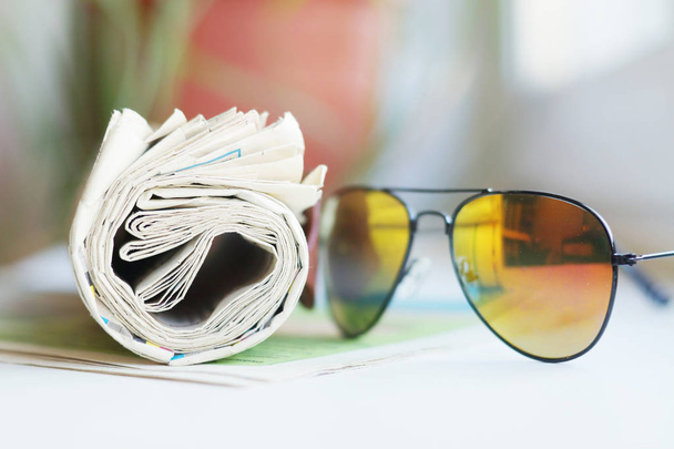 Quotidiani e occhiali da sole arrotolati, focus selettivo
      - Foto, immagini