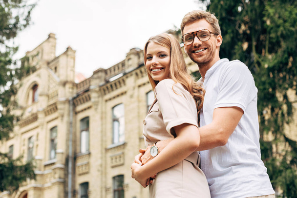 bottom view of beautiful young couple embracing near old building - Photo, Image