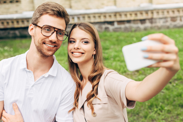 beautiful young couple taking selfie in front of green grass - Foto, afbeelding
