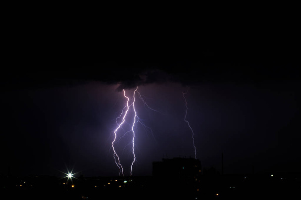 Burza pioruna nad miastem w fioletowym świetle - Zdjęcie, obraz