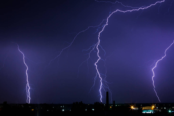 Burza pioruna nad miastem w fioletowym świetle - Zdjęcie, obraz