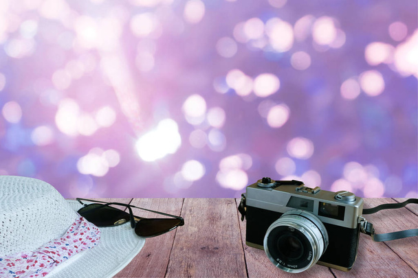 Eski film kamerası, güneş gözlüğü ve şapka eski ahşap masa bulanık mavi bokeh arka plan ile ön plan üzerinde. Hazırlamak seyahat kavramı - Fotoğraf, Görsel