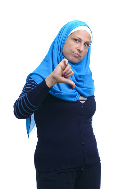 Mulher muçulmana moderna bonita com polegares para baixo sinal isolado em fundo branco - Foto, Imagem