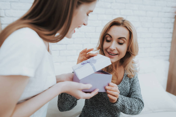 Smiling Daughter Gives Mother Gift in Small Box. Relationship in Family. Holiday at Home. Happy Mother. Friendly Relations. Celebrating Together. Happiness in Family Concept. Presenting Gift. - Foto, Imagem