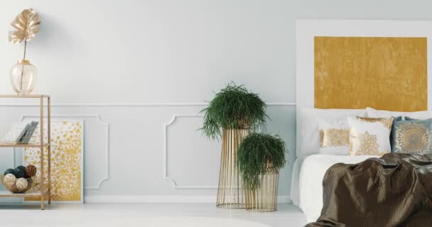 Witte en grijze kussens met gouden patroon op het bed in elegante slaapkamer interieur met goud schilderij. Video met het veranderen van frames - Video