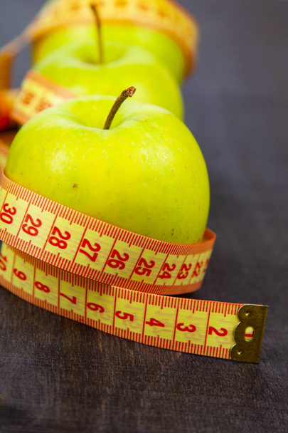 Apples and measuring tape  on a dark wooden background, top view. Concept of diet and healthy lifestyle. - Fotó, kép
