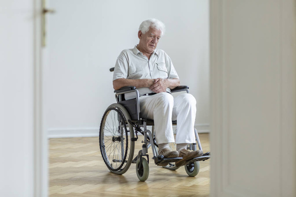 Sad paralyzed senior man in the wheelchair sitting alone at home - Valokuva, kuva