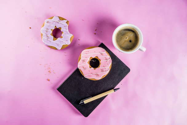 Conceito de descanso e relaxamento, xícara de café e biscoitos donut com revestimento de açúcar, com um bloco de notas ou desejos em um fundo moderno brilhante, espaço de visão superior para texto
 - Foto, Imagem