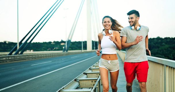 Attractive man and beautiful woman jogging together on bridge - Zdjęcie, obraz