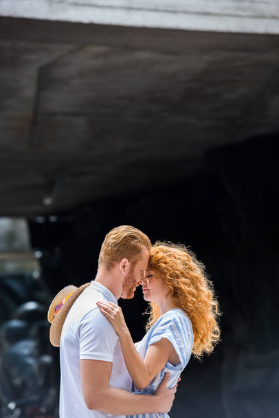 side view of redhead couple embracing each other and standing face to face at cit street  - Fotoğraf, Görsel