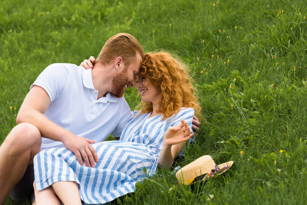 smiling redhead couple looking at each other face to face on grassy meadow - Foto, immagini