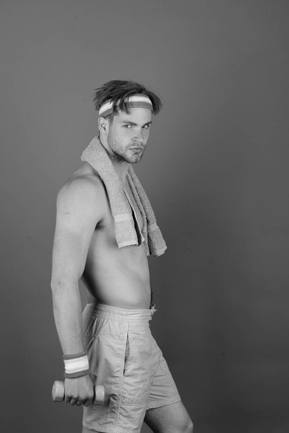 Man with naked torso holds towel on neck and dumbbell - Fotografie, Obrázek