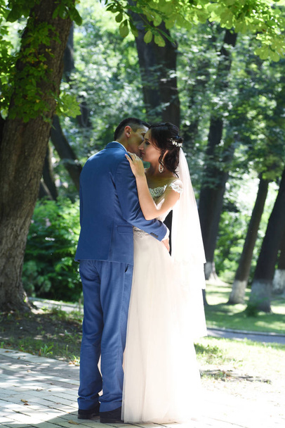 Vista completa de la encantadora pareja de boda abrazándose y besándose en el parque
 - Foto, imagen