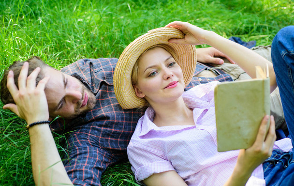Man and girl lay on grass reading book. Family enjoy leisure with poetry or literature book grass background. Couple soulmates at romantic date. Couple in love spend leisure reading book in park - Фото, изображение