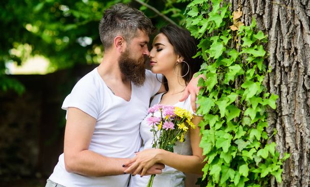 Gentle kiss. Man bearded hipster hugs gorgeous girlfriend. Couple in love going to kiss. Pleasant romantic kiss. Couple love romantic date nature park background. Love relations romantic feelings - Photo, image