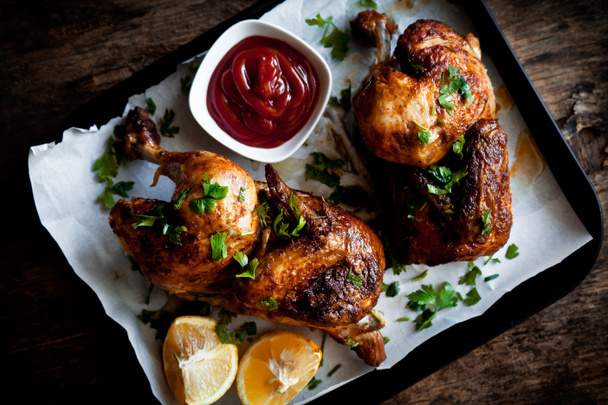 Halves of a roasted chicken with herbs and ketchup - Fotografie, Obrázek