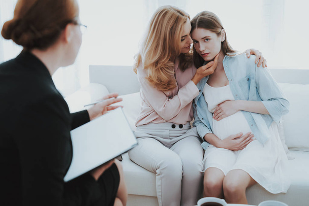 Mother with Pregnant Daughter in Doctor Office. Visit to Family Doctor. Consulting Psychologist. Healthy Pregnancy Concept. Young Mother. Worried Mother. Pregnant Girl. Psychological Help. - Foto, afbeelding