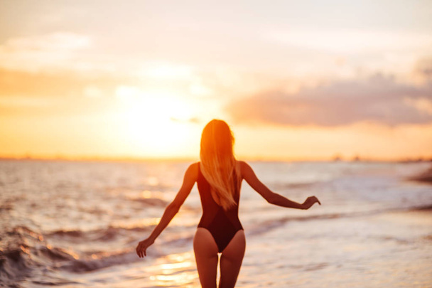 carefree woman dancing in the sunset on the beach. vacation vitality healthy living concept - Foto, Imagen