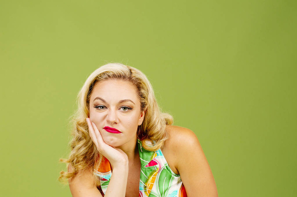 Portret van een bored en ongelukkig blonde vrouw, geïsoleerd op groene studio pagina - Foto, afbeelding