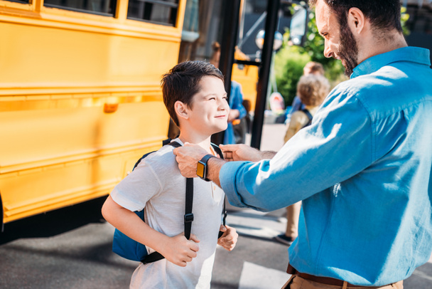 pai feliz de pé com seu filho na frente do ônibus escolar
 - Foto, Imagem
