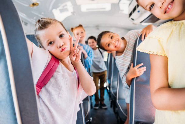 group of happy schoolchildren riding on school bus and looking at camera - Foto, imagen