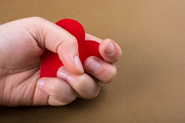 Red color heart shaped object in hand  on dotted paper - 写真・画像