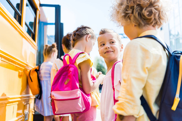 close-up shot of group of adorable schoolchildren standing near school bus - Fotografie, Obrázek