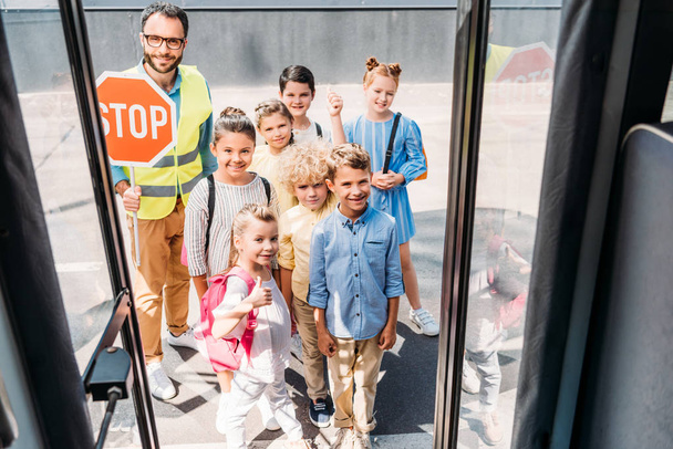 vue de l'autobus scolaire à un groupe d'élèves avec un garde de la circulation regardant la caméra
 - Photo, image