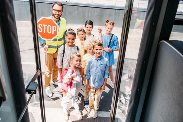 kameraya bakarak trafik bekçi ile okul otobüs grubu mutlu bilim adamlarının görüntülemek - Fotoğraf, Görsel