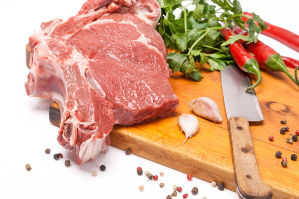 świeże mięso wołowiny z kością na drewniane przyprawy i nóż - Zdjęcie, obraz