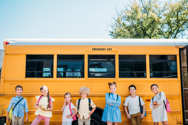группа очаровательных учеников, позирующих перед школьным автобусом
 - Фото, изображение