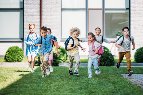 Gruppe liebenswerter Schüler läuft durch den Schulgarten - Foto, Bild