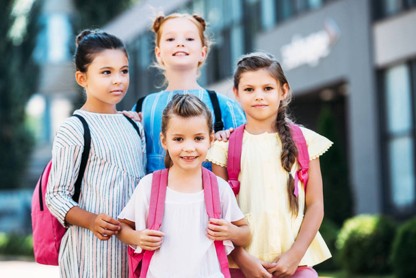 group of adorable schoolgirls with backpacks looking at camera - Photo, image