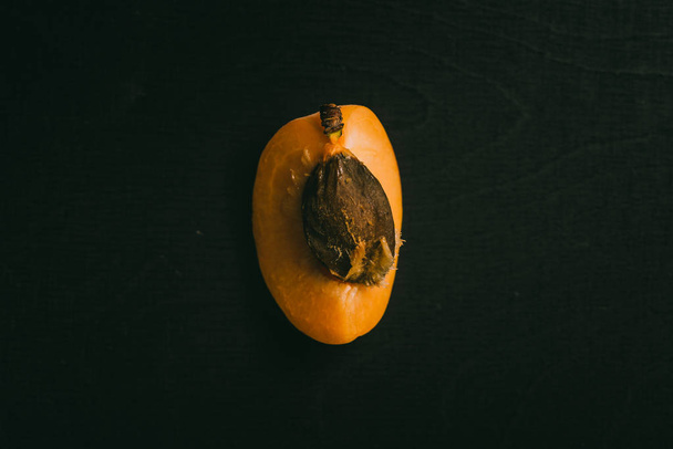 Cut peach with seed lying on black chalkboard in background with copy space from above as flat lay - Photo, image
