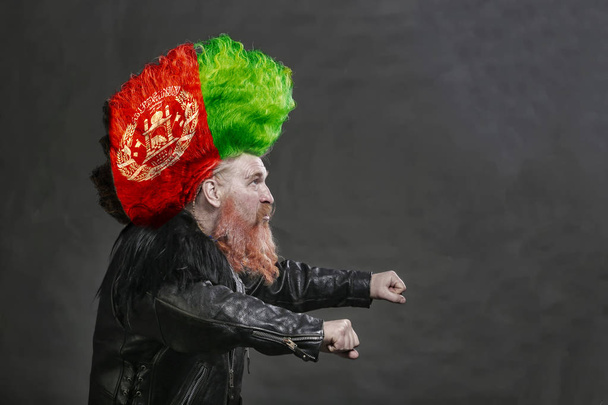 closeup portrait adult biker in black leather jackets and high mohawk with the Afghan flag  - Fotó, kép