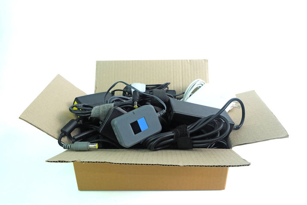 Boîte en papier avec le chargeur d'alimentation adaptateur endommagé ou ancien d'ordinateur portable ou d'appareils électriques sur fond blanc
 - Photo, image