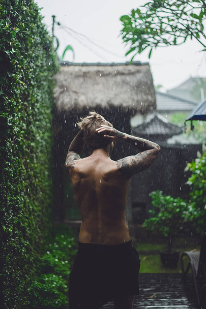 joven hombre tatuado posando bajo la lluvia
 - Foto, imagen