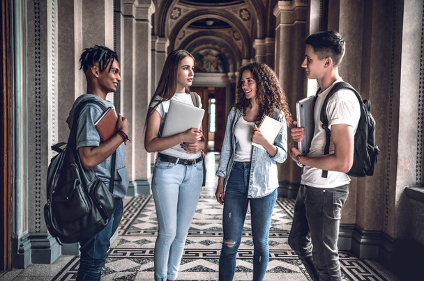 Students life. Four beautiful students chatting each other in the university. - Zdjęcie, obraz
