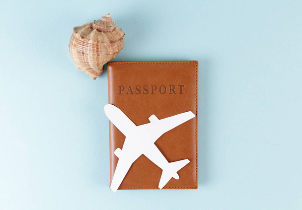 Passport, seashell and airplane cut out on blue background. - Fotografie, Obrázek