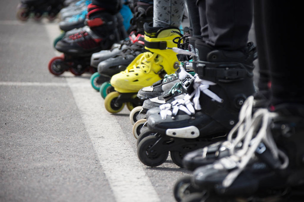 Крупный план колес для катания на коньках. Ноги в роликовых коньках выстроены в ряд
 - Фото, изображение